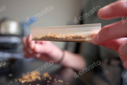 Preview: Young woman making a marijuana cigarette for health reasons