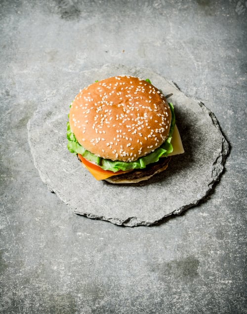 Preview: Fresh Burger with cheese and meat on a stone stand.