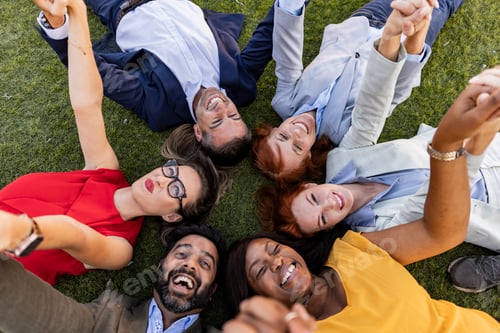 Preview: Group of multi ethnic business people lying in a circle holding hands