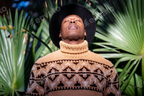 Preview: Relaxing black man in hat standing with closed eyes