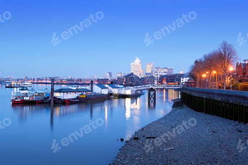 Preview: UK, London, floating workshops on River Thames and Canary Wharf in background at blue hour