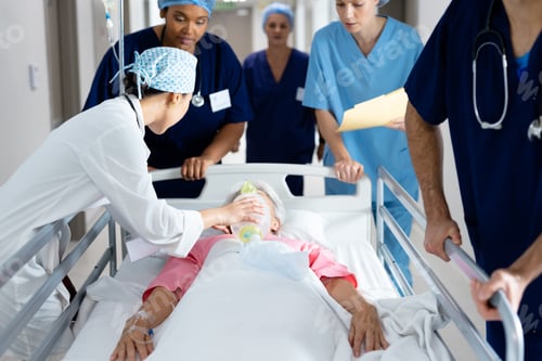 Preview: Diverse group of healthcare workers giving ventilator to patient in bed in hospital corridor