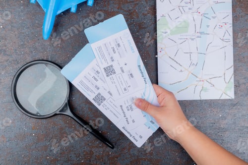Vista previa: top view of female hands holding plane tickets with magnifying glass on a black background