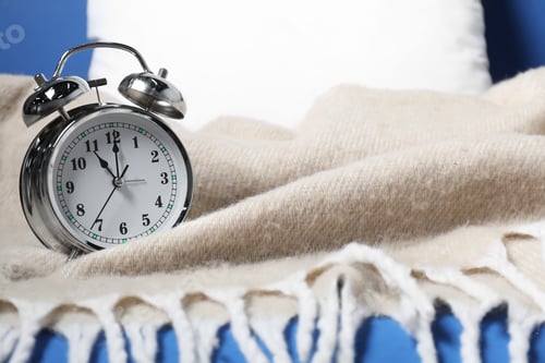 Preview: Alarm clock, pillow and blanket on blue background, closeup. Time for sleeping