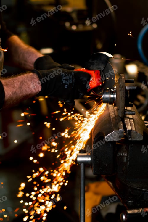 Preview: close-up of car mechanic working at a service station with an angle grinder from which sparks fly