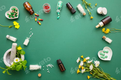 Preview: Homeopathy, globules and herbs on green background