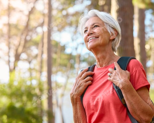 Preview: Happy Senior Woman Hiking Through Sunny Forest