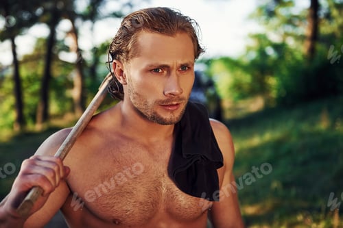 Preview: Handsome shirtless man with muscular body type is in the forest at daytime