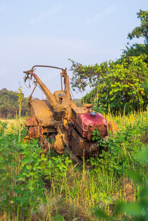 Preview: Vertical shot of rusty farm equipment in an abandoned field under the light