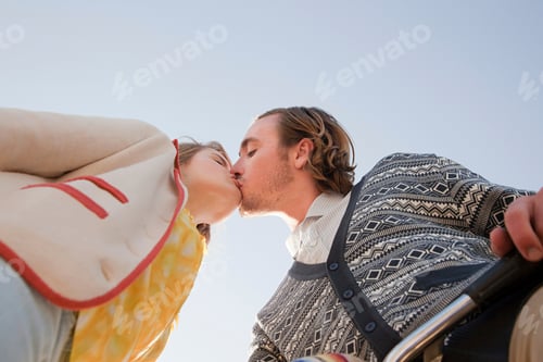 Preview: Couple sharing a romantic kiss under a clear sky
