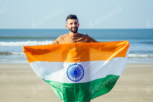 Preview: Indian young man waving indian tricolour flag outdoor near beach,