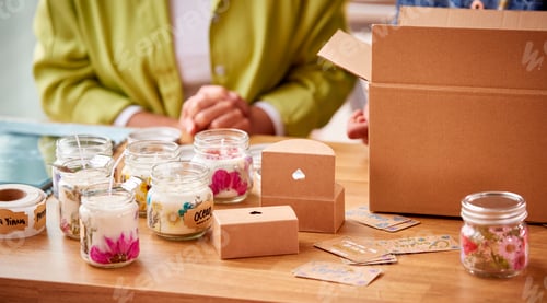 Preview: Close Up Of Couple Running Online Business From Home Packing Boutique Candles Ready For Shipping