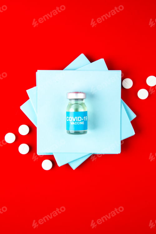 Preview: top view blue paper stickers with pills and vaccine drawing on red background vaccine covid- color
