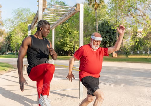 Preview: Elderly man exercising with resistance band and personal trainer in a calisthenics park