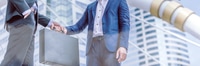 Preview: Businessmen Handshake Over Briefcase Near Modern Building