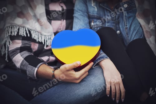 Preview: Family hands holding a heart in Ukrainian colors