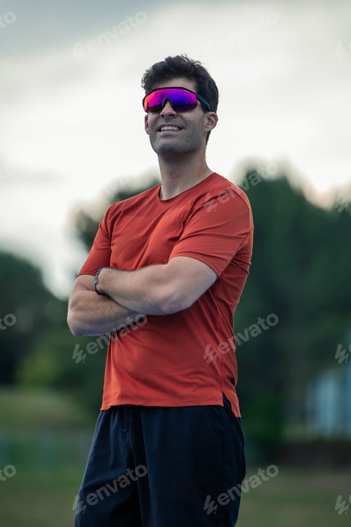 Preview: vertical Outdoor Portrait of Sportsman with Sunglasses Posing with Crossed Arms