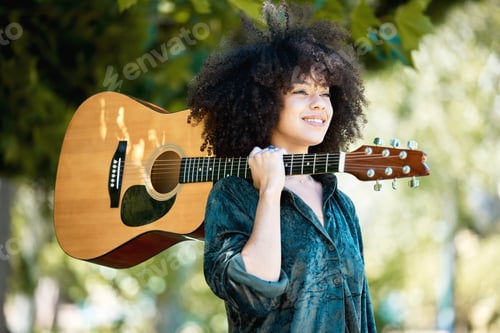 Preview: Happy smiling young mixed race female musician holding her guitar while standing snd enjoying a rel