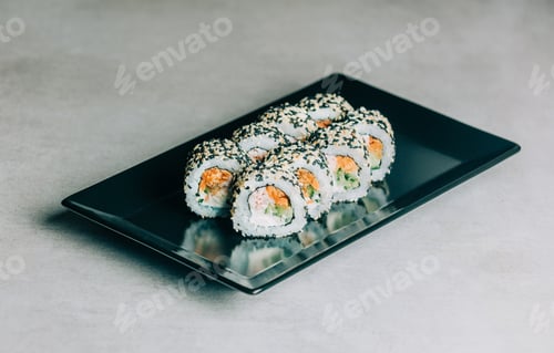 Preview: sushi rolls in sesame with salmon on black plate on gray background