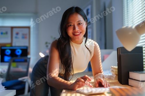Preview: Asian businesswoman smiling calculating finances in office