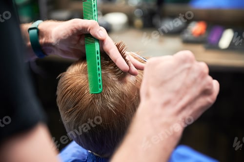 Preview: Cropped photo of barber making haircut for little boy.