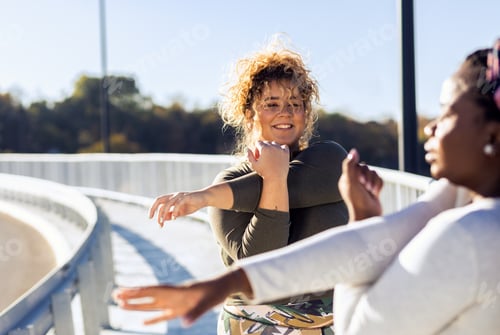 Preview: Two young plus size women stretching together before running.