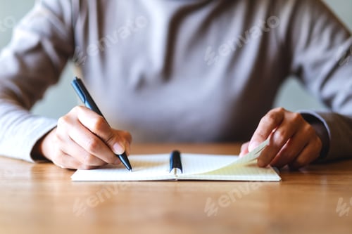 Preview: Closeup image of a woman writing on a blank notebook on the table