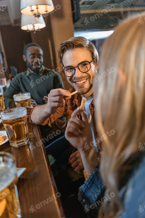 Preview: attractive multiculture friends eating and drinking at bar