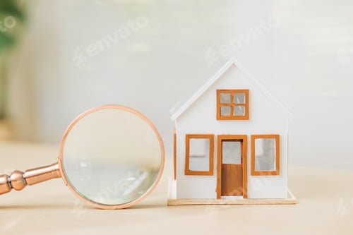 Preview: Magnifying glass with a white house model represents property search and finance.