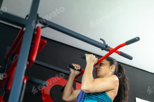 Preview: Determined sportswoman doing pull ups on assisted pull up machine in gym