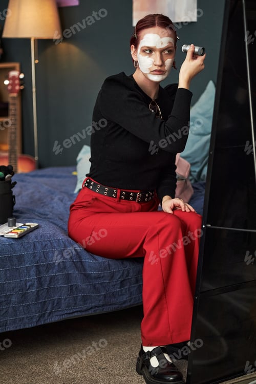 Preview: Caucasian Teenager Girl Applying Creative Face Paint While Sitting Indoors