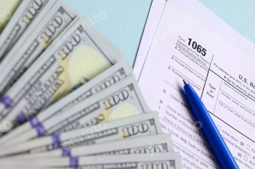 Preview: 1065 tax form lies near hundred dollar bills and blue pen on a light blue background