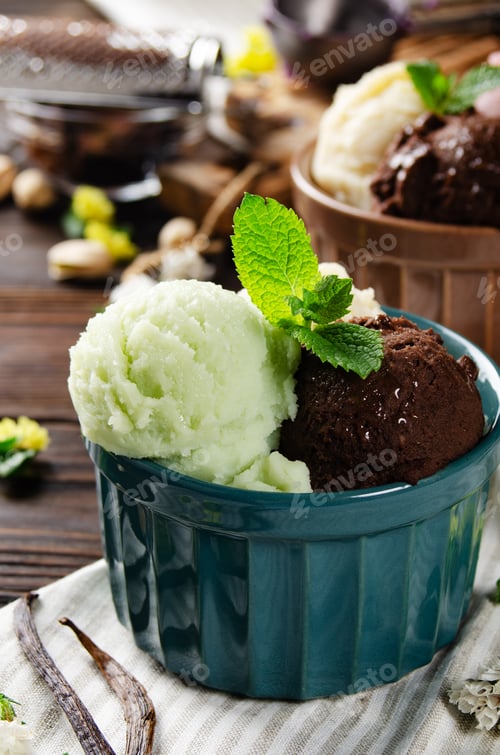 Preview: Three scoops of Vanilla pistachio and chocolate icecream balls in clay bowls on wooden kitchen table