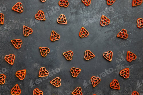 Preview: top view scattered italian red heart pasta on dark background