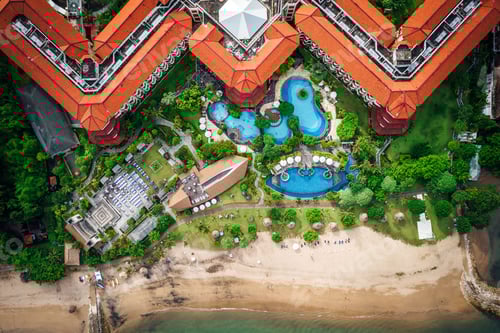 Preview: Aerial view of a symmetrical building of a resort surrounded by lush vegetation nearby body of water