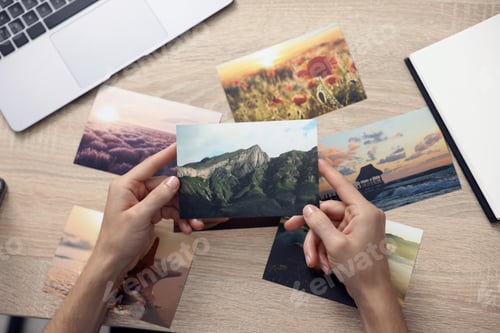 Preview: Professional photographer working with photos at wooden table, top view