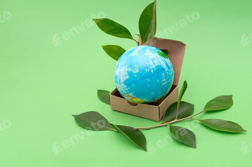 Preview: Earth Globe in Cardboard Box with Green Leaves on Green Background