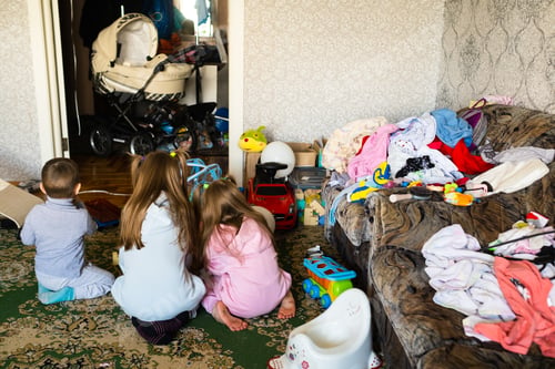 Preview: Three unrecognizable children are playing in a dirty cluttered room