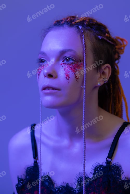Preview: Cinematic night portrait of woman face with shiny make-up with sequins illuminated neon light