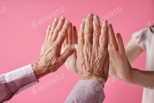 Preview: Senior Caucasian Woman and Young Girl Touching Hands Against Pink Background