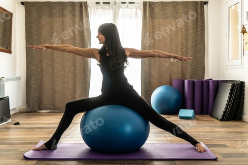 Preview: A woman doing yoga with fitness ball in studio