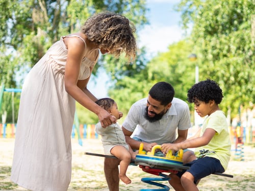 Preview: Latin family playing together in a playground with their children, a boy and a baby