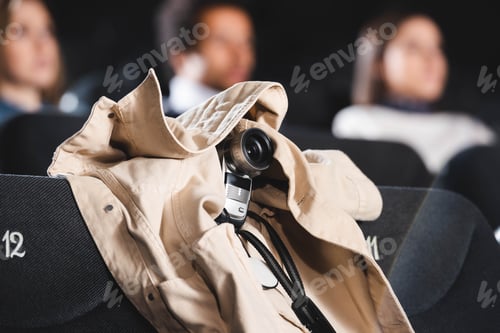 Preview: selective focus of digital camera covered in coat shooting movie in cinema