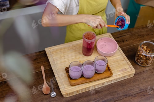 Preview: Woman making delicious desert chia puddings with strawberry and blueberry, almond milk