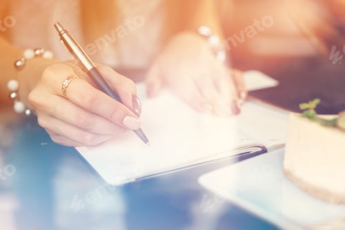 Preview: Woman making notes while sitting in a coffee shop