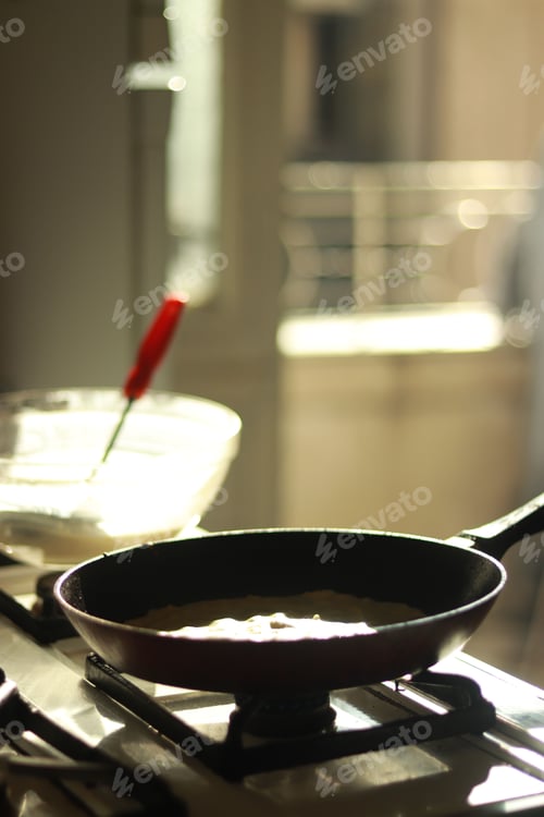 Preview: Vertical selective focus of a frying pan on a gas stove next to a glass bowl in the kitchen