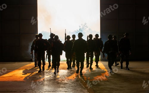 Preview: Silhouette of soldiers walking against smoke and sunset background.