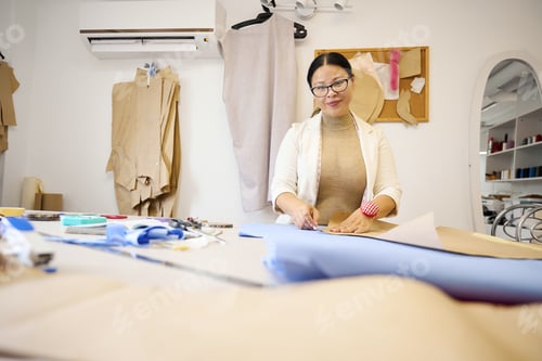 Preview: Craftswoman at her workplace cuts blue fabric