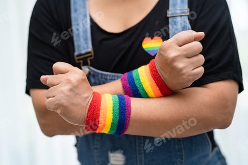 Preview: Asian lady wearing rainbow flag wristbands, symbol of LGBT pride month celebrate annual in June