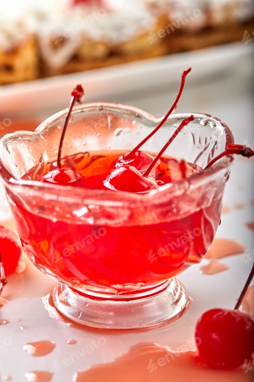 Preview: Cherries in sugar with sprigs lie in a cherry syrup in a transparent bowl on a light background